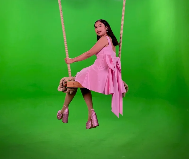 Vrouw in een roze jurk op een grote schommel in de green screen studio van Studio2Go in Haarlem