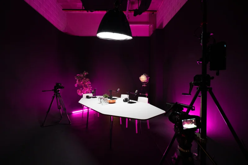 Podcast setting in de zwarte studio van Studio2Go met roze lampen