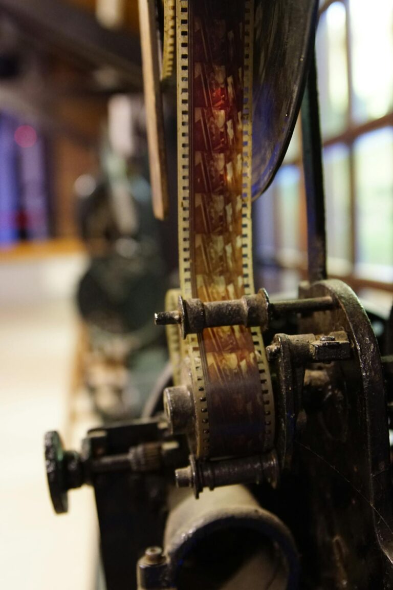 From above of vintage movie camera with film roll on metal feed spool near window in cinematography studio